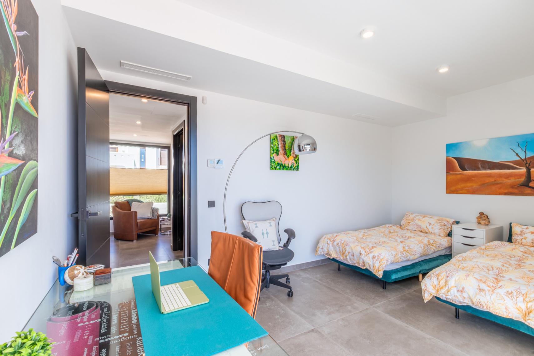 Dormitorio luminoso con dos camas individuales, zona de despacho integrada y suelos de gres porcelánico. La estancia cuenta con iluminación empotrada y acceso directo al pasillo.