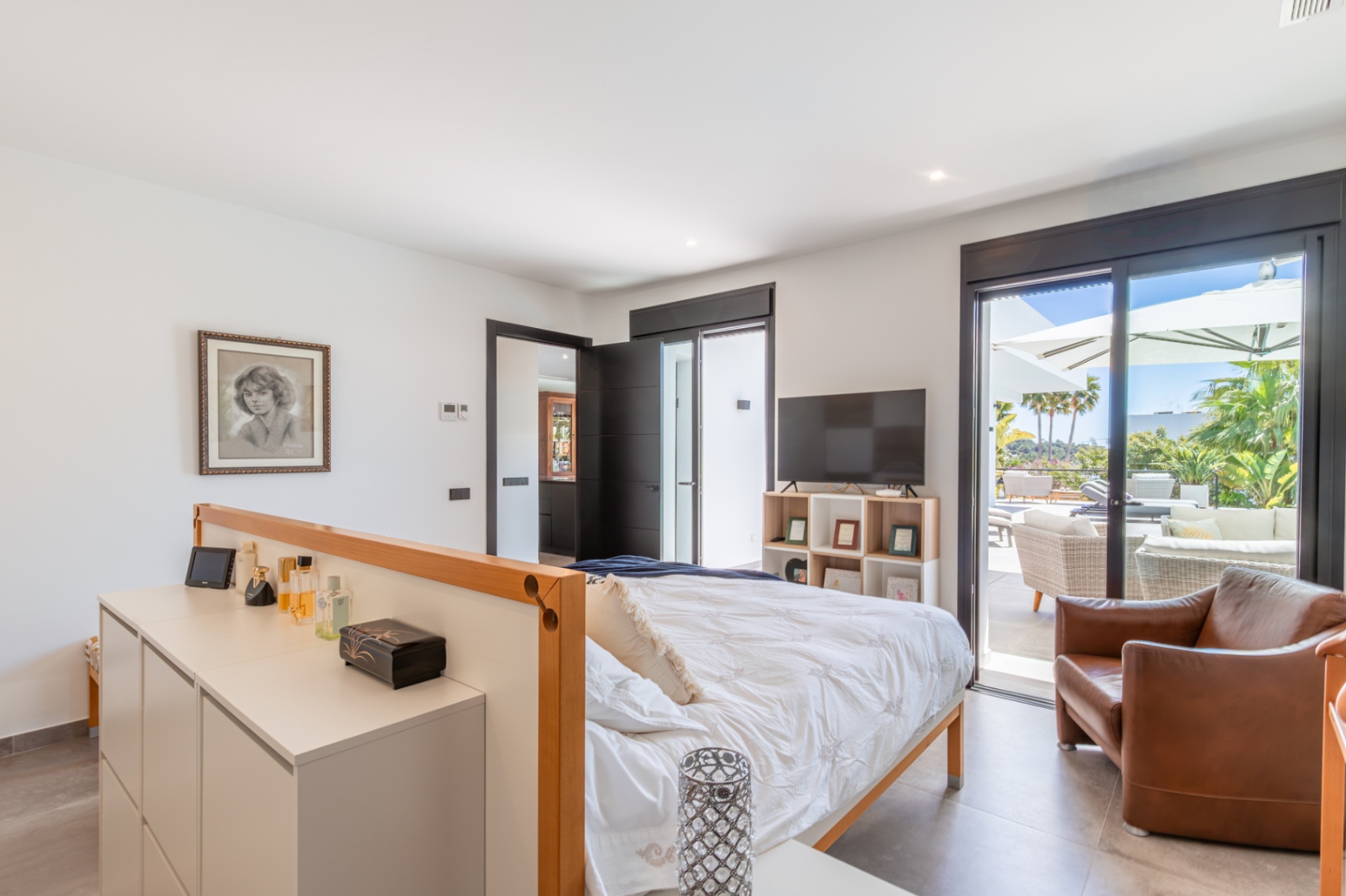 Dormitorio principal con acceso directo a la terraza, grandes ventanales correderos y una distribución funcional que integra mobiliario de diseño y luz natural.