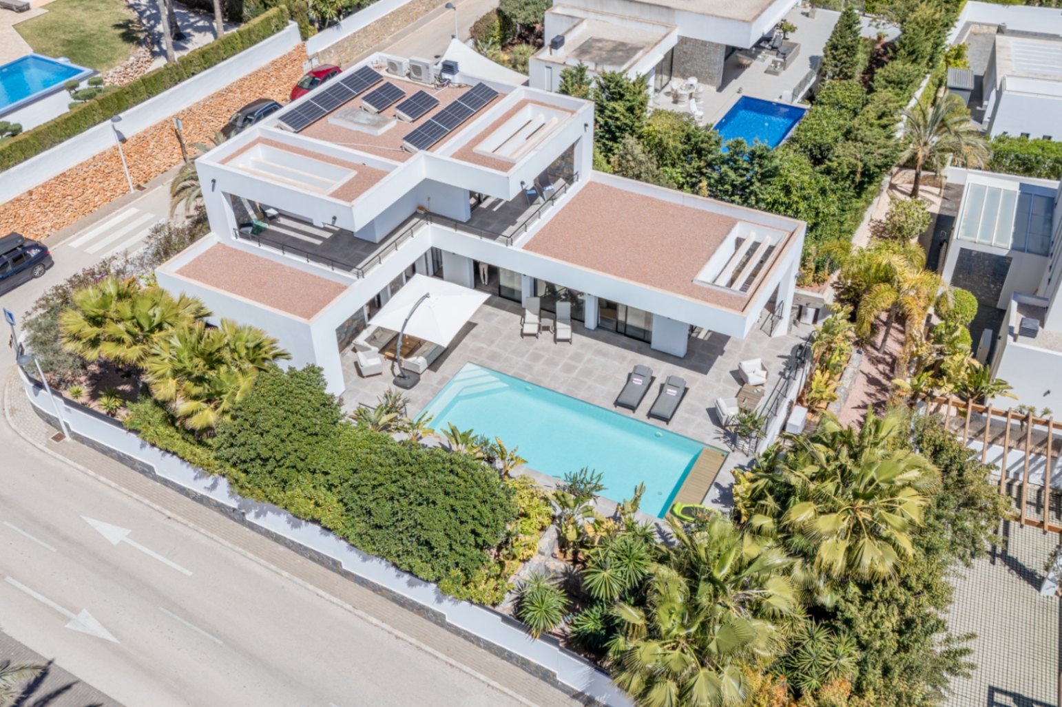Vista aérea de la villa moderna con paneles solares, piscina rectangular y amplias terrazas rodeadas de vegetación mediterránea privada en Solpark.
