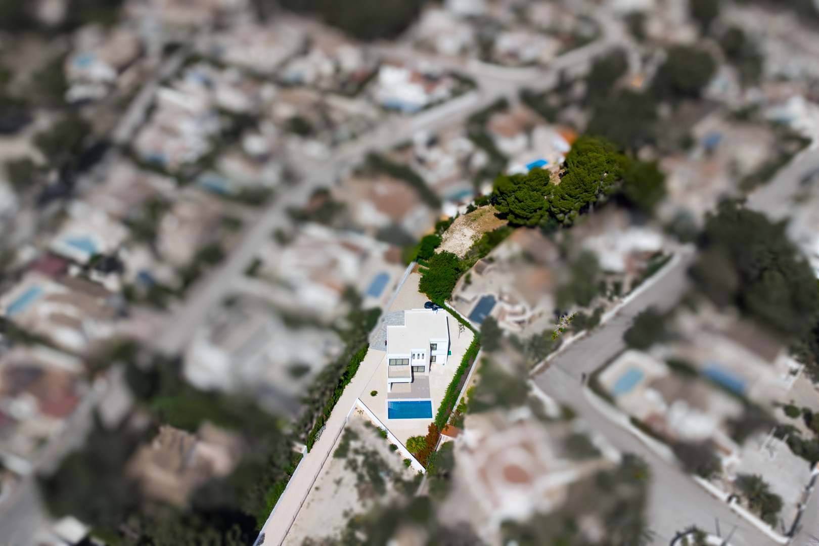 Vista aérea cenital de la villa sobre su amplia parcela llana, destacando la piscina rectangular y la gran zona de terreno adicional privativo en La Fustera.