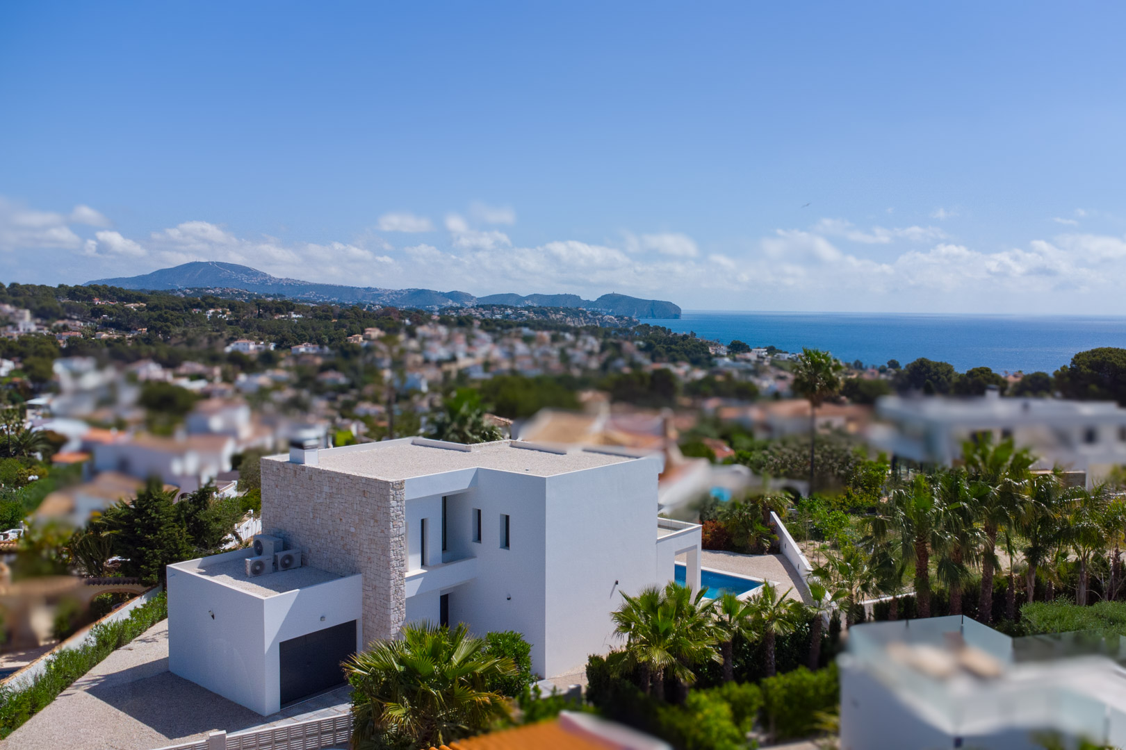 Vista aérea de la villa de diseño moderno con fachada de piedra natural, piscina privada y vistas panorámicas al mar Mediterráneo en La Fustera.