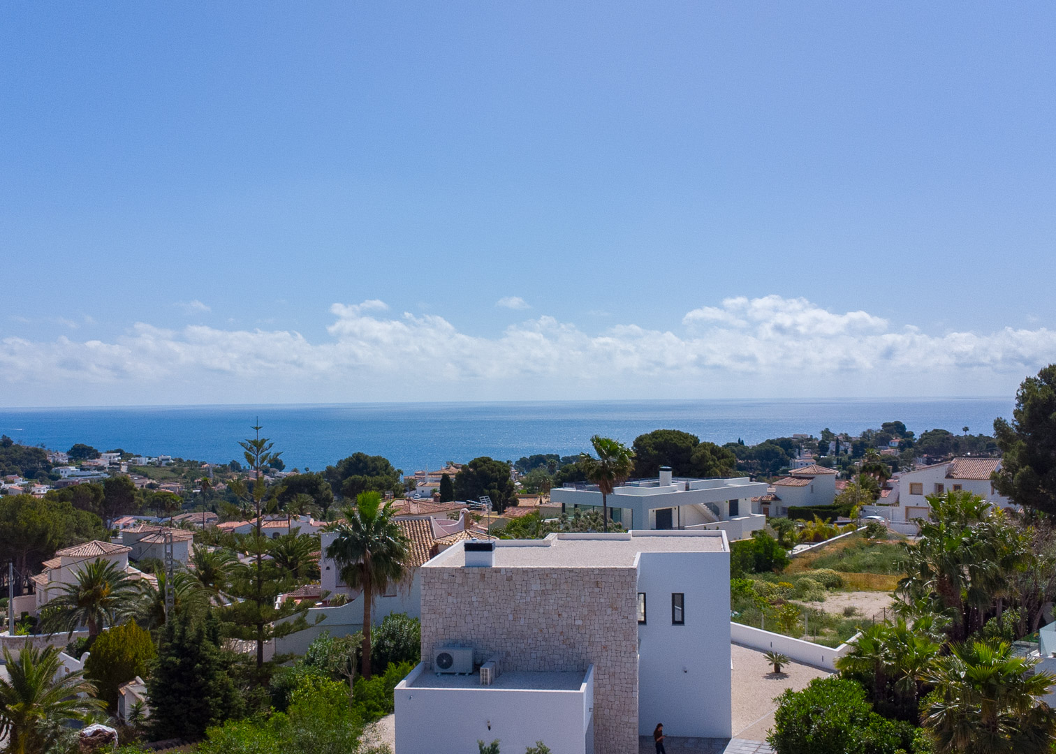 Vista elevada de la arquitectura moderna con acentos de piedra natural, destacando las vistas panorámicas al mar Mediterráneo y el entorno verde de Benissa.