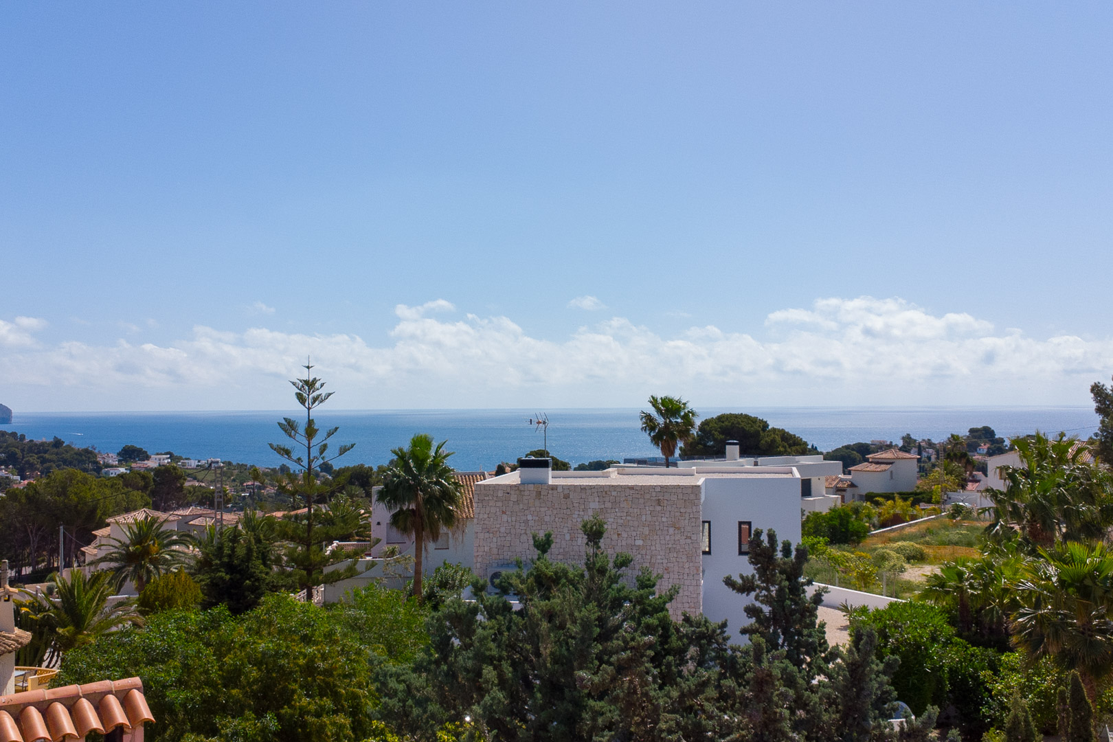 Vista panorámica desde la propiedad hacia el mar Mediterráneo, mostrando la arquitectura blanca de Benissa y la vegetación local bajo un cielo despejado.