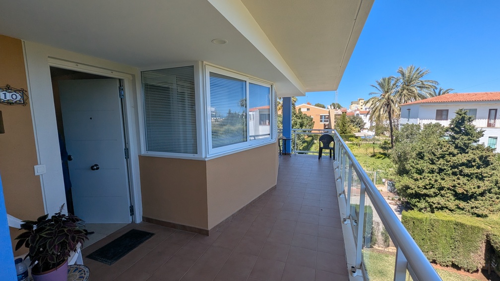 Amplia terraza privada con suelo de baldosas marrones, barandilla de cristal y cerramiento parcial. Ofrece vistas a palmeras y al paisaje residencial local. Amplia terraza privada con suelo de baldosas marrones, barandilla de cristal y cerramiento parcial. Ofrece vistas a palmeras y al paisaje residencial local.