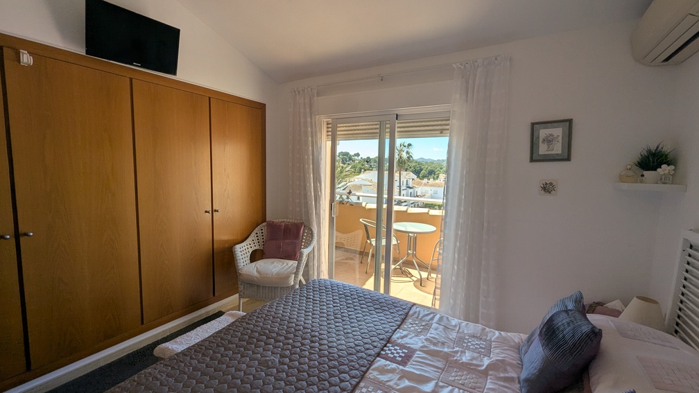 Dormitorio principal con amplio armario empotrado de madera, aire acondicionado y acceso directo a una terraza privada con vistas despejadas.