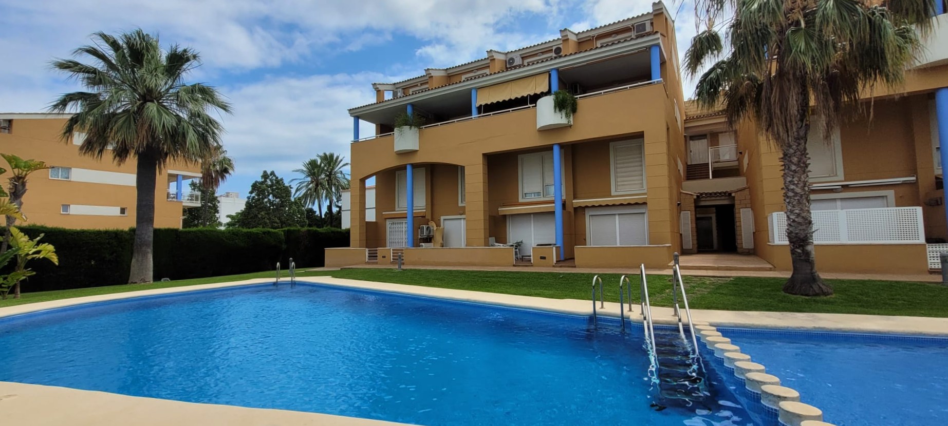 La atractiva piscina comunitaria de agua azul cristalina, rodeada de césped cuidado y palmeras, complementa la fachada ocre del edificio con pilares azules en los balcones. La atractiva piscina comunitaria de agua azul cristalina, rodeada de césped cuidado y palmeras, complementa la fachada ocre del edificio con pilares azules en los balcones.