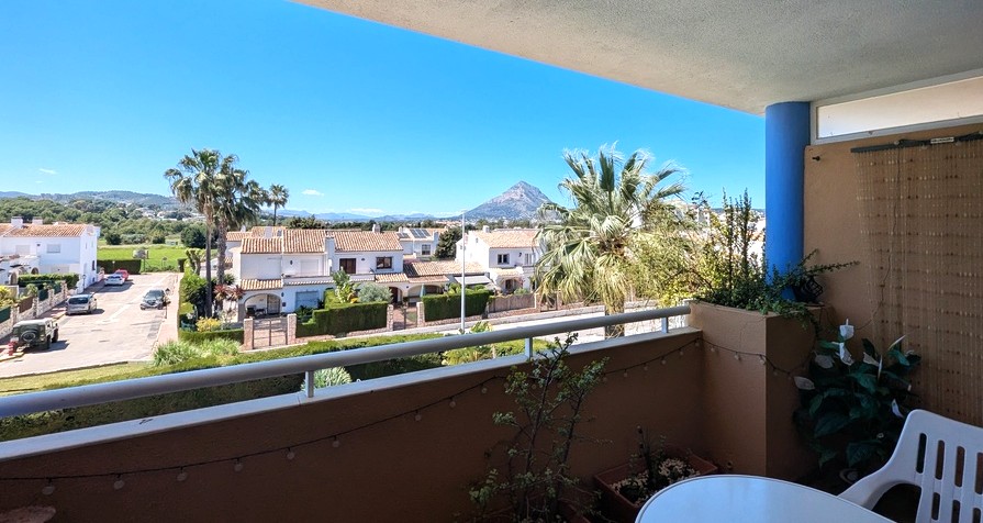 Terraza abierta con barandilla blanca y plantas, ofreciendo vistas panorámicas a residencias locales, zonas verdes y la distintiva montaña del Montgó bajo un cielo despejado. Terraza abierta con barandilla blanca y plantas, ofreciendo vistas panorámicas a residencias locales, zonas verdes y la distintiva montaña del Montgó bajo un cielo despejado.