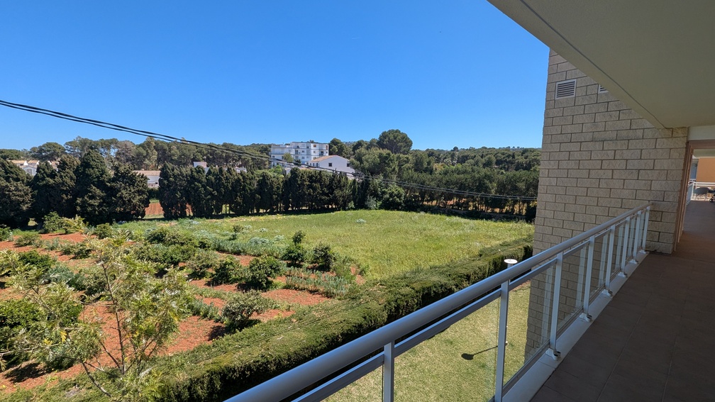Vista desde la terraza privada con barandilla moderna de cristal y metal, ofreciendo un paisaje de campos verdes, arboledas y edificios distantes bajo cielo azul. Vista desde la terraza privada con barandilla moderna de cristal y metal, ofreciendo un paisaje de campos verdes, arboledas y edificios distantes bajo cielo azul.