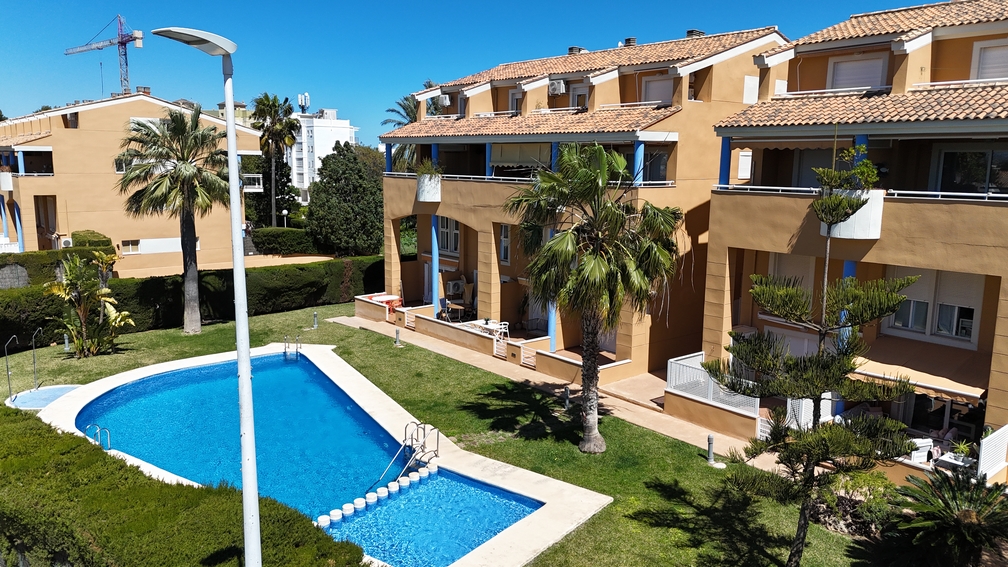 Vista elevada de la gran piscina comunitaria y el área infantil, rodeadas de césped cuidado y palmeras, con edificios residenciales al fondo. Vista elevada de la gran piscina comunitaria y el área infantil, rodeadas de césped cuidado y palmeras, con edificios residenciales al fondo.