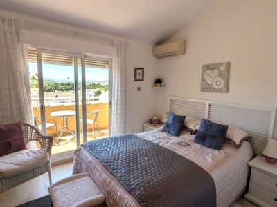 El dormitorio principal ofrece una cama doble con cabecero de lamas, aire acondicionado y acceso directo a una terraza privada con vistas al paisaje.