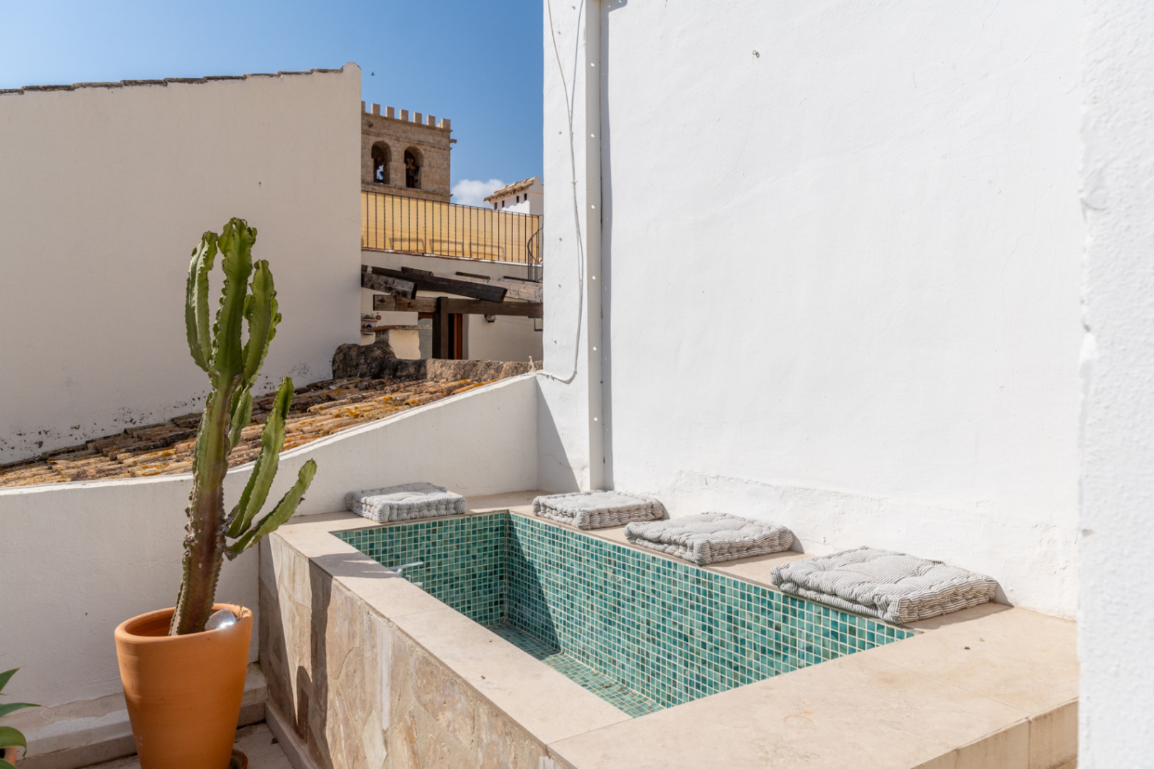Detalle de la terraza con piscina de mosaico turquesa y vistas al casco antiguo de Jávea.