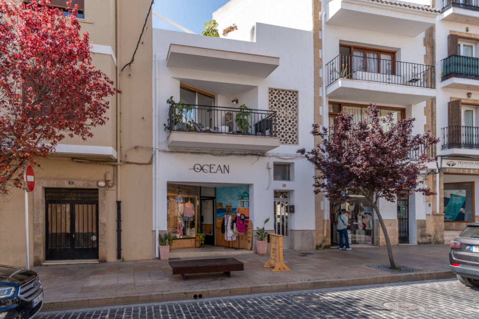 Fachada renovada de edificio de apartamentos en el casco antiguo, con balcón y tienda a nivel de calle.