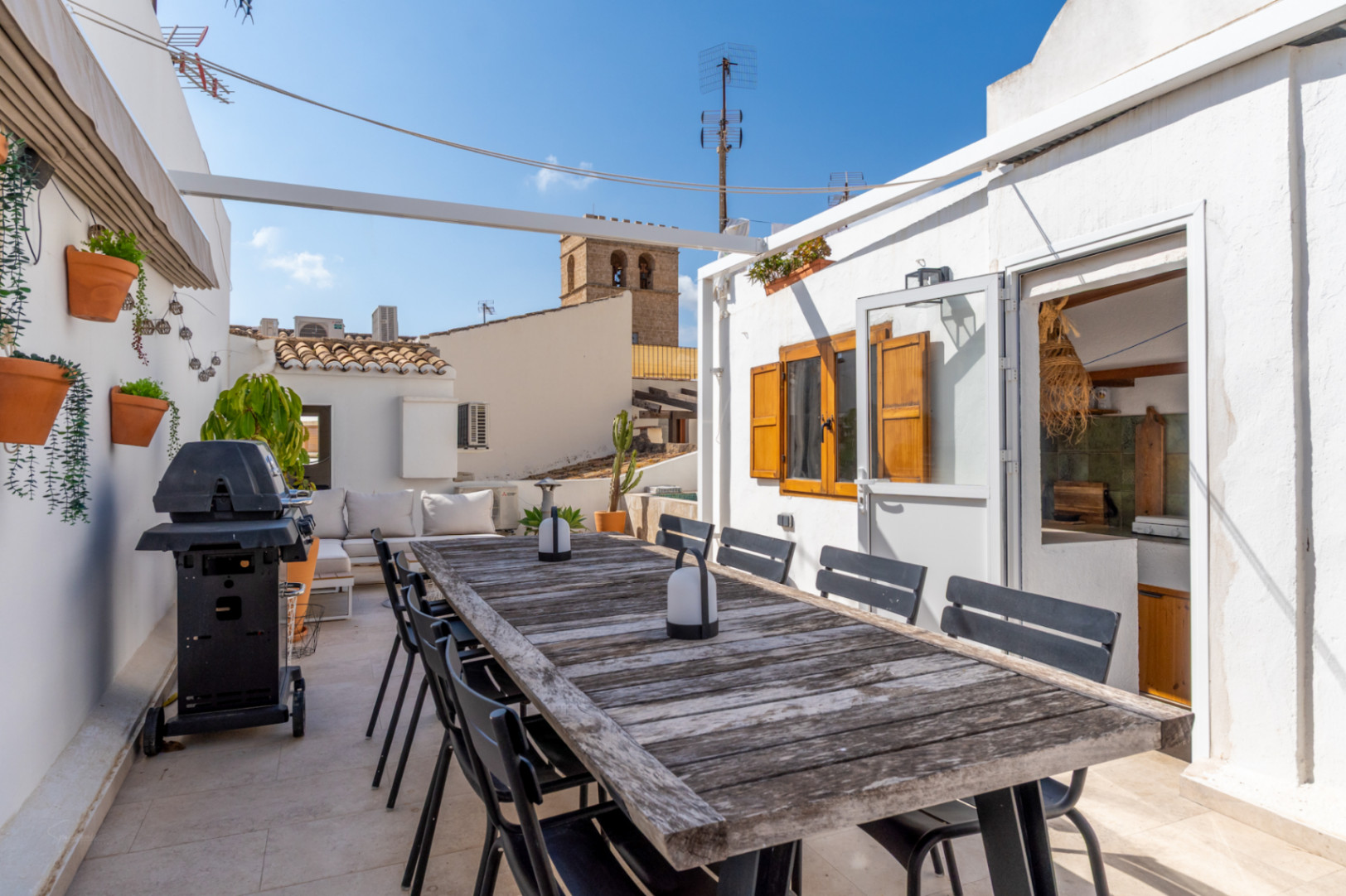 Terraza con mesa de madera rústica, barbacoa y vistas al casco antiguo de Jávea.