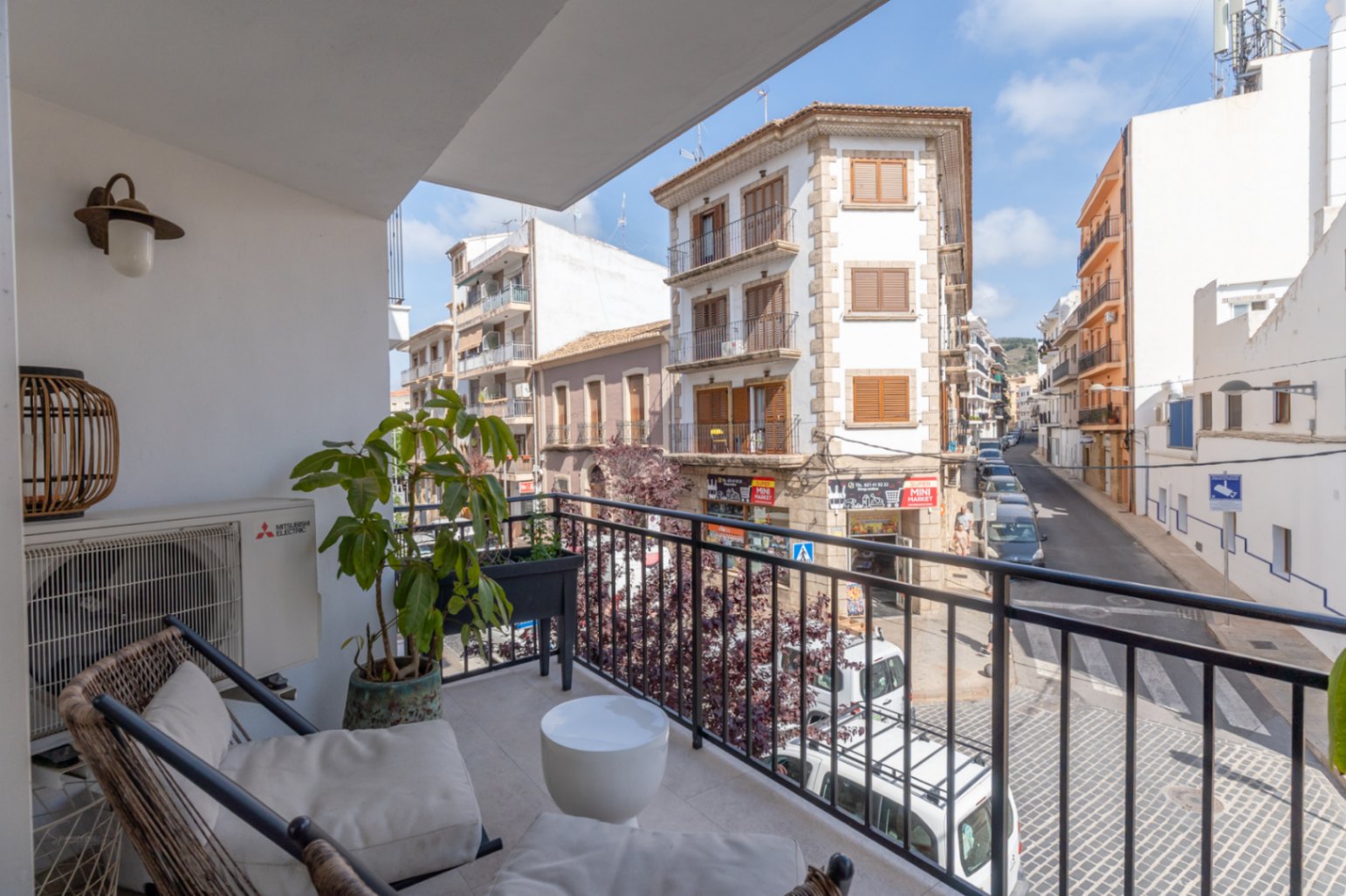 Terraza con vistas a la calle en el centro histórico de Jávea, con mobiliario de exterior y plantas ornamentales.