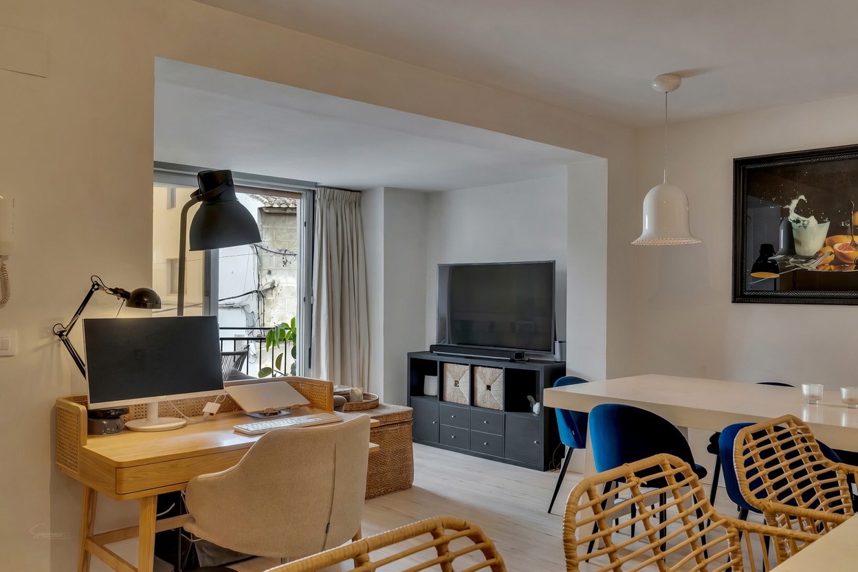 Vista del salón-comedor con escritorio de madera clara y acceso al balcón en Jávea.
