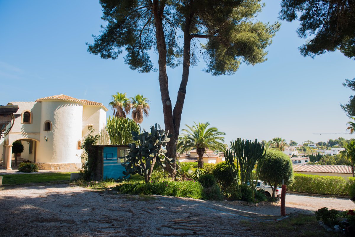 Vista exterior de la villa mediterránea con detalles arquitectónicos únicos y jardines exuberantes.