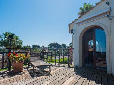Terraza soleada con suelo de madera, tumbona y vistas al paisaje mediterráneo.