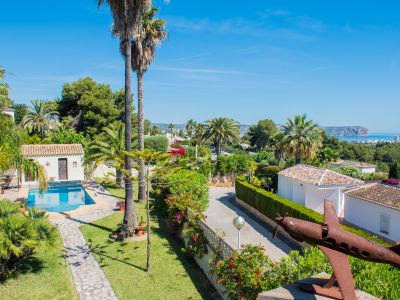 Vista elevada del jardín mediterráneo con piscina y escultura de avión oxidada en Jávea.