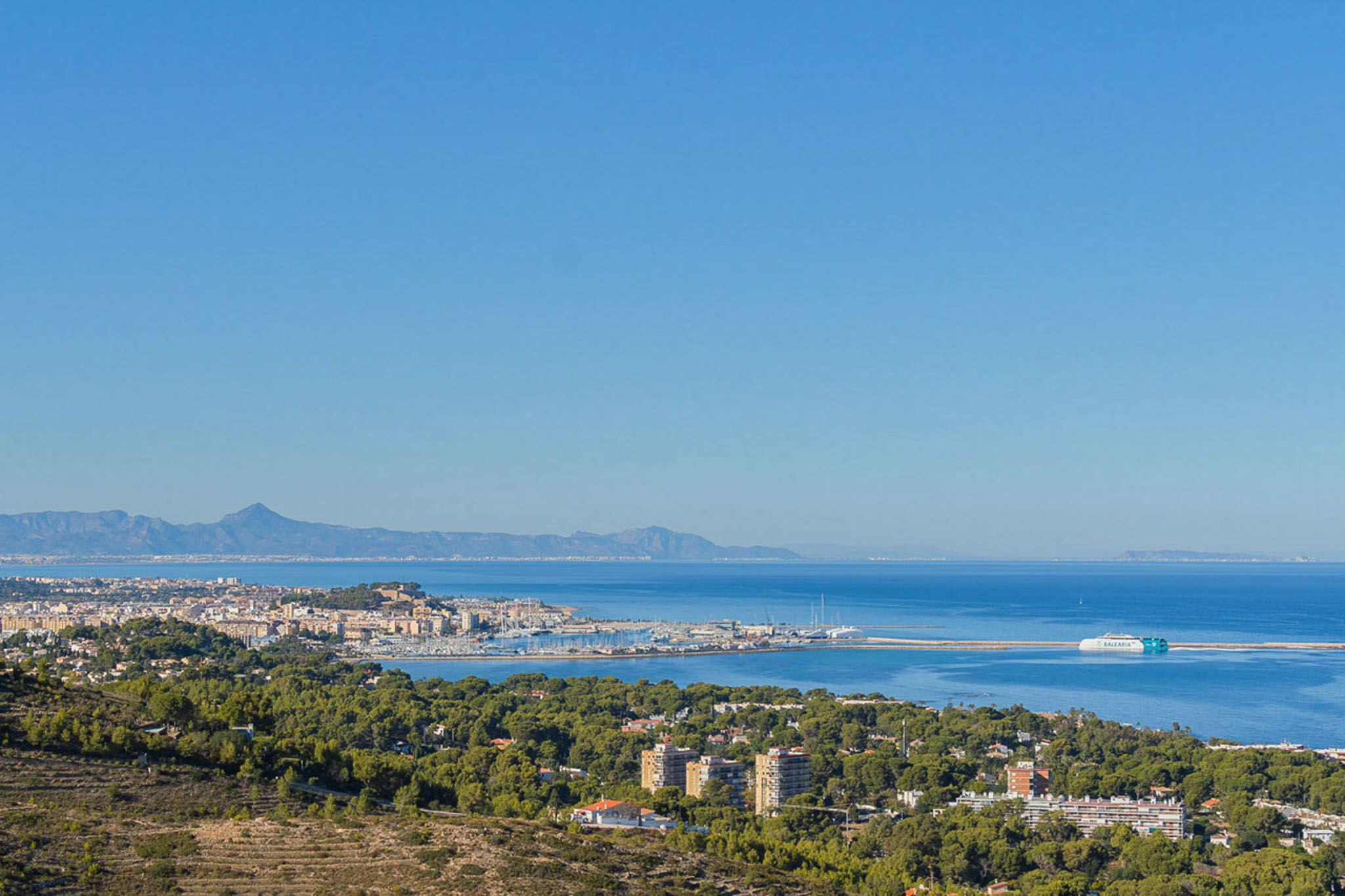 Vista panorámica desde la propiedad hacia el puerto de Dénia y el mar Mediterráneo, con el ferry de Baleària y el perfil de la costa en el horizonte.