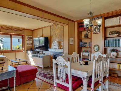 Comedor con estanterías de madera y mesa rústica blanca con cojines rojos.