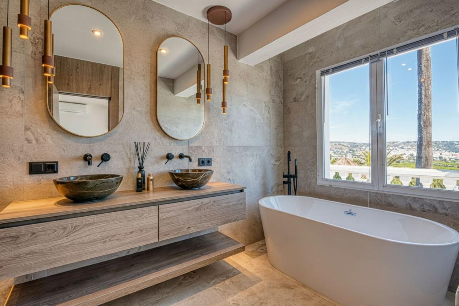 Elegante baño con lavabos de piedra sobre encimera de madera, bañera exenta y vistas panorámicas.