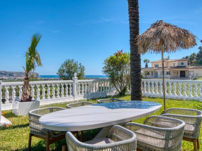 Comedor exterior con mesa de mármol y vistas al mar Mediterráneo desde el jardín de la villa.