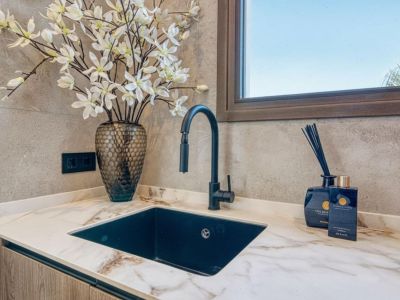 Detalle de encimera con lavabo negro, grifo moderno y decoración floral. Elegancia y funcionalidad en la cocina.