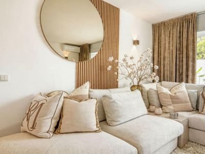 Detalle del salón con sofá modular tapizado en beige y pared decorativa de madera.