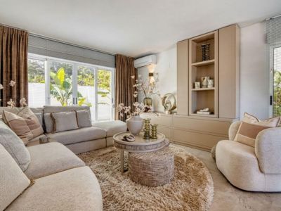 Salón luminoso con sofá modular, alfombra redonda de felpa y mueble de almacenamiento integrado.