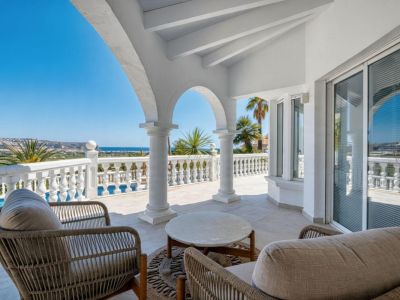 Terraza cubierta con arcos de piedra, mobiliario de ratán y vistas panorámicas al mar Mediterráneo.