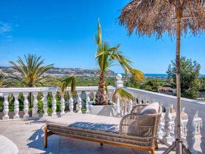 Terraza soleada con tumbona de ratán y vistas panorámicas a Jávea.