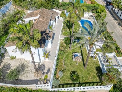 Vista aérea de la villa con jardín, piscina y terraza. Diseño mediterráneo con muros blancos y vegetación exuberante.
