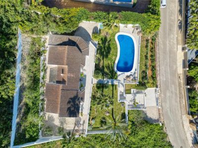 Vista aérea de la villa con piscina azul brillante, rodeada de jardines y vegetación exuberante en Jávea.