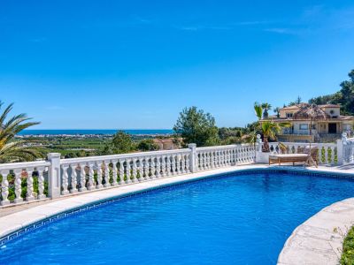 Vista de la piscina con barandilla de balaustres blancos y vistas al mar Mediterráneo y al paisaje de Jávea.