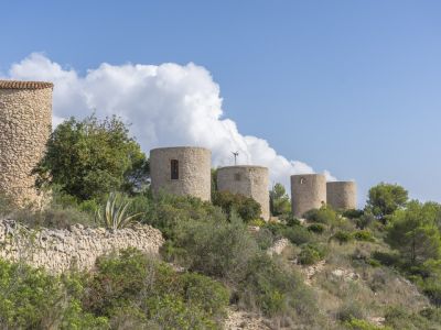 Vista de los históricos molinos de viento de piedra en Jávea, integrados en el paisaje mediterráneo.