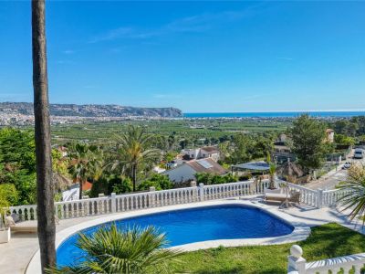 Vista elevada de la piscina con barandilla blanca y vistas panorámicas al mar y la ciudad.