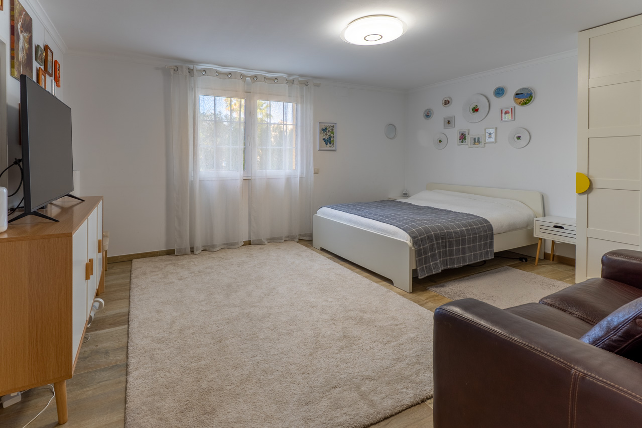 Dormitorio luminoso con cama blanca, alfombra de felpa y detalles decorativos en la pared.