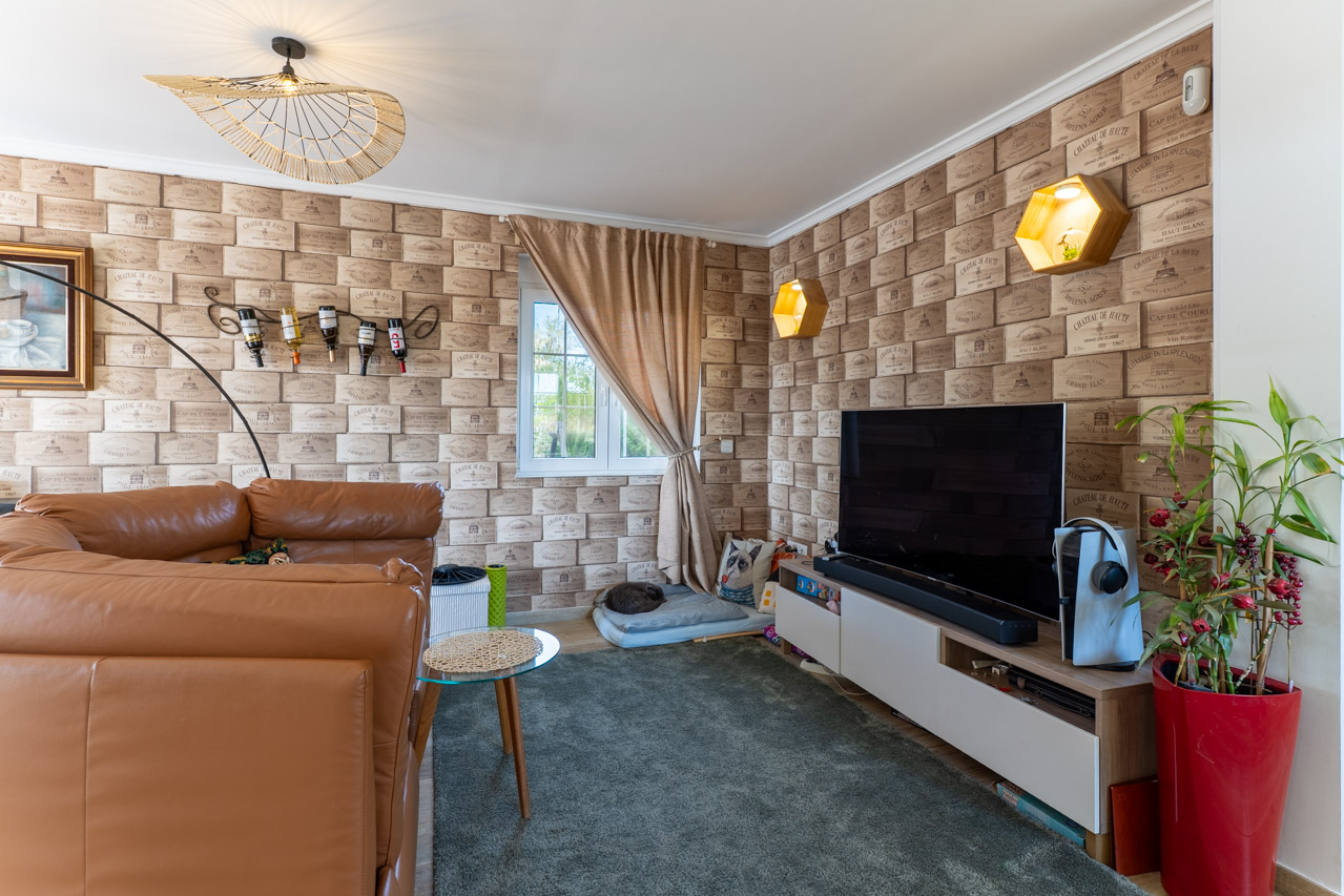Salón con pared decorada con papel pintado de cajas de vino y sofá de cuero marrón.