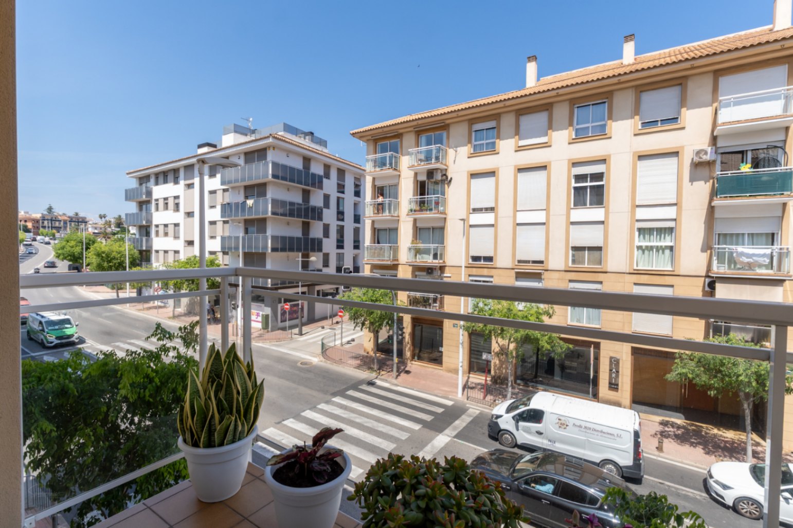Vista desde el balcón con barandilla metálica, macetas con plantas ornamentales y edificios residenciales.