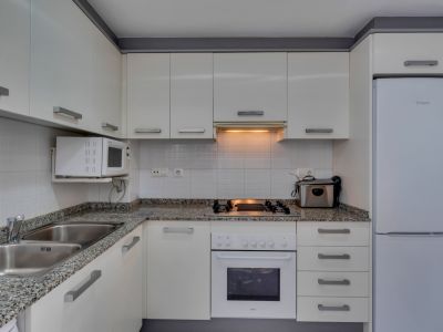 Cocina funcional con encimera de granito, electrodomésticos blancos y luz cálida.