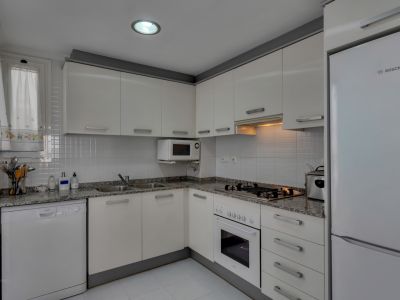 Cocina funcional con encimera de granito, electrodomésticos blancos y luz cenital.