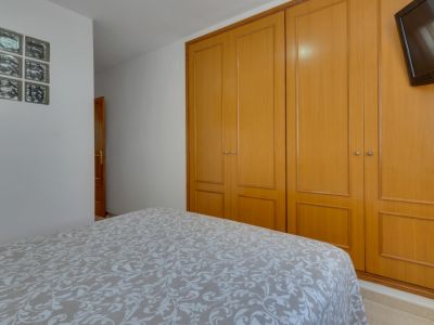 Dormitorio luminoso con cama doble y armario empotrado de madera. Decoración funcional y minimalista.
