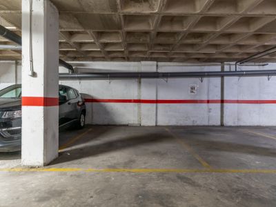 Plaza de aparcamiento subterráneo con suelo de hormigón y techo artesonado.