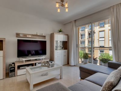 Salón luminoso con mobiliario moderno y acceso a balcón con vistas urbanas.