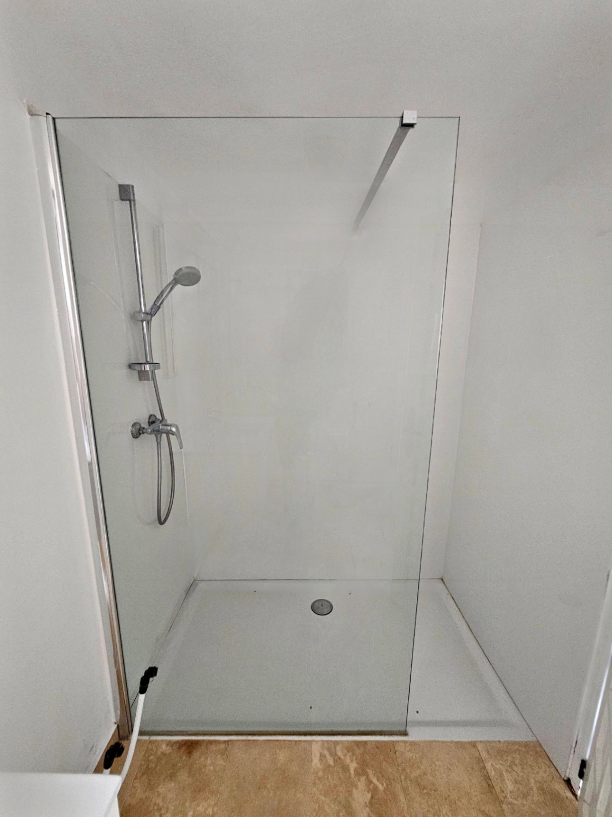 Detalle de la ducha con mampara de cristal y grifería de acero en baño moderno.