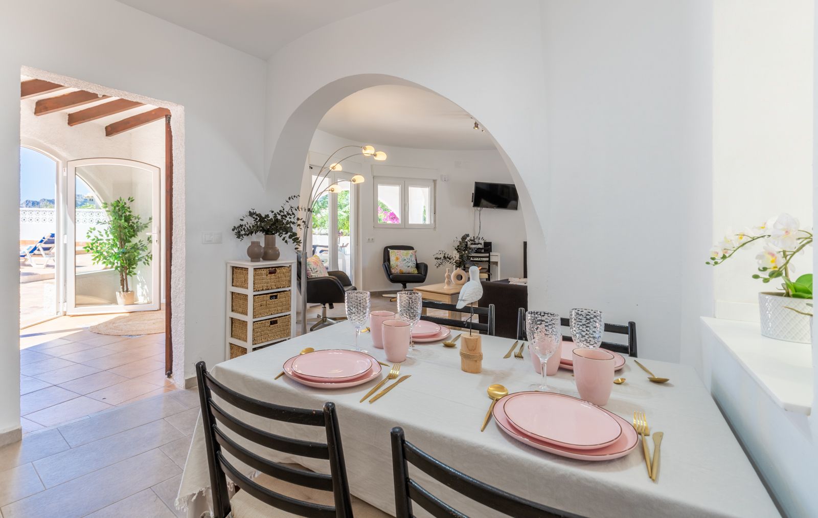 Comedor luminoso con mesa preparada en tonos rosa y dorados, con acceso a la terraza y salón. Comedor luminoso con mesa preparada en tonos rosa y dorados, con acceso a la terraza y salón.