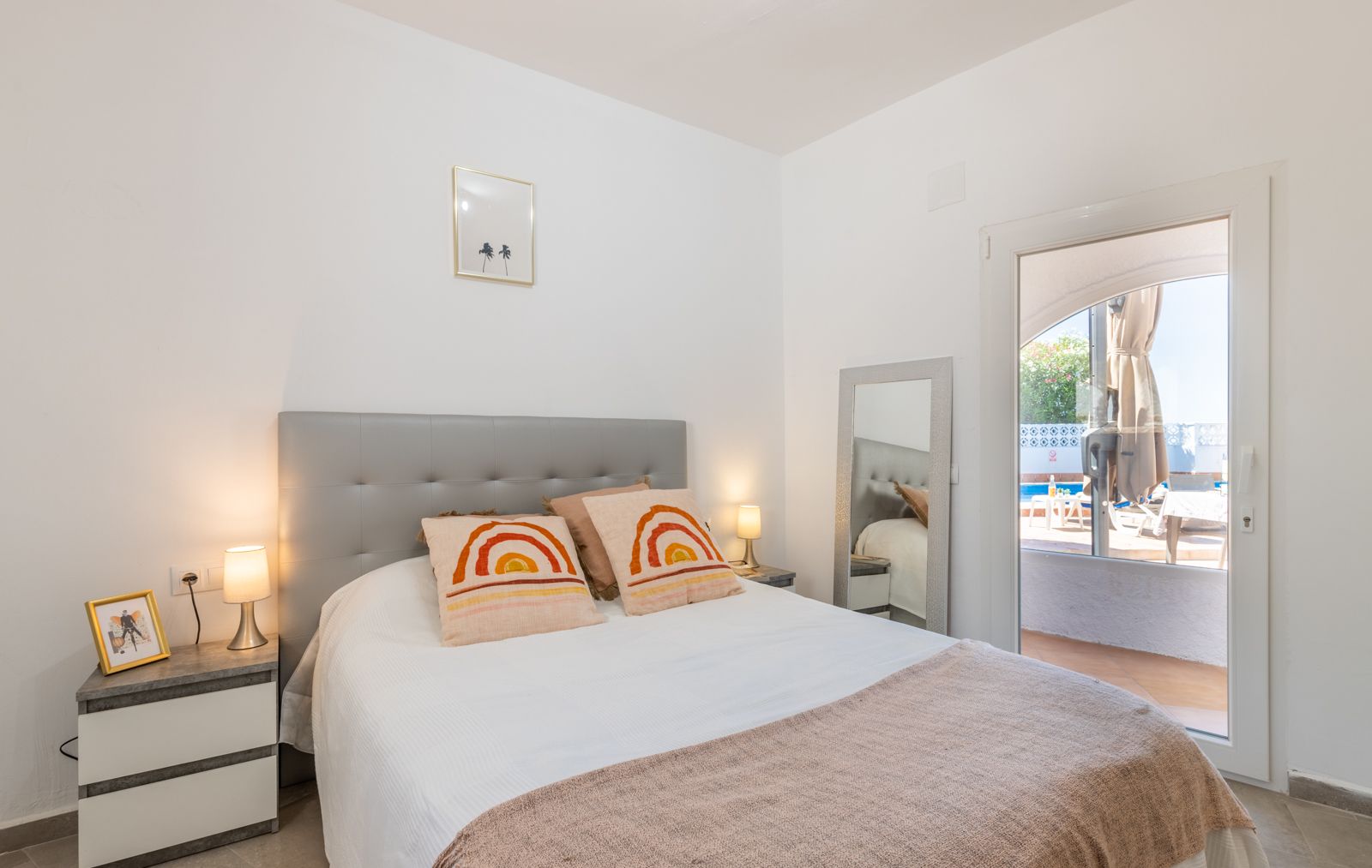 Dormitorio luminoso con cabecero gris, ropa de cama blanca y acceso directo a la piscina. Dormitorio luminoso con cabecero gris, ropa de cama blanca y acceso directo a la piscina.
