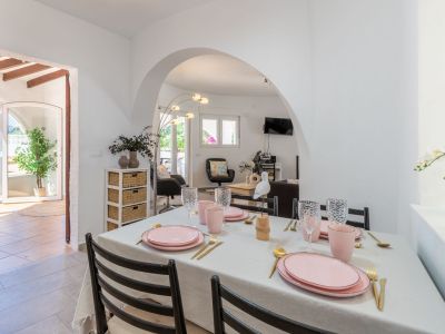 Comedor luminoso con mesa preparada en tonos rosa y dorados, con acceso a la terraza y salón.