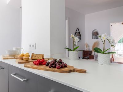 Detalle de la encimera de la cocina con frutales y flores, mostrando un diseño moderno y luminoso.