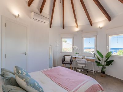 Dormitorio luminoso con techo abovedado de vigas de madera y escritorio con vistas al mar.